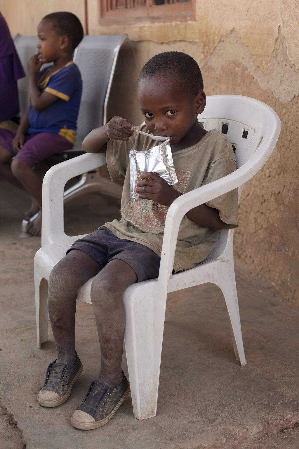 Child eating ready-to-use therapeutic food outside a clinic